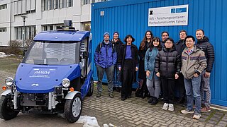 Mehrere Personen stehen neben einem Elektrofahrzeug