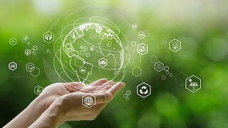 Symbolbild, 2 Hände halten eine durchsichtige Weltkugel, um die Kugel herum weitere grafische Symbole. Der Hintergrund ist grün-verwischt