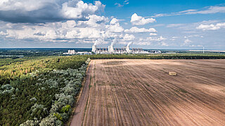 Ein Acker mit Industrieanlage im Hintergrund