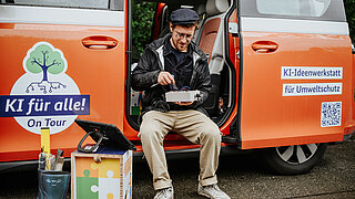 Ein Mann sitzt in der Schiebetür eines Busses und prüft ein Gerät. 