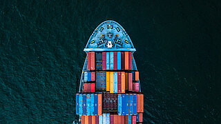 Der vordere Teil eines Frachtschiffes schiebt sich über das Wasser. 