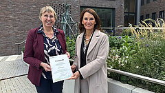 2 Personen halten eine Urkunde bzw. einen Förderbescheid in die Kamera